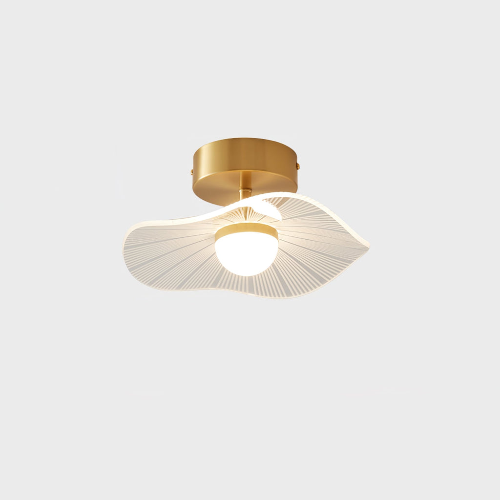 Brass-fitted ceiling light, front-on, with its ribbed wavy shade and warm glowing globe, on a pale grey ground, a Clérachic ceiling light.