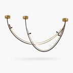 Three-point arc ceiling light from Clérachic, with brass canopies and black frame arcs holding white light strips, on a white background.