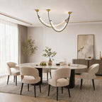 Clérachic arc pendant hanging above an oval dining table with cream chairs, with an abstract print and a fluted sideboard beyond.