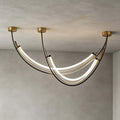 Close view of the black leather-wrapped arcs and the glowing white silicone strips of this Clérachic pendant, against a grey plaster ceiling.