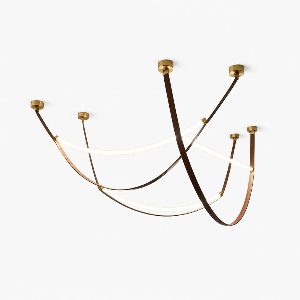 A set of three Clérachic leather-loop pendants on a white backdrop, each brown strap swooping between gold ceiling caps with a lit LED strip.