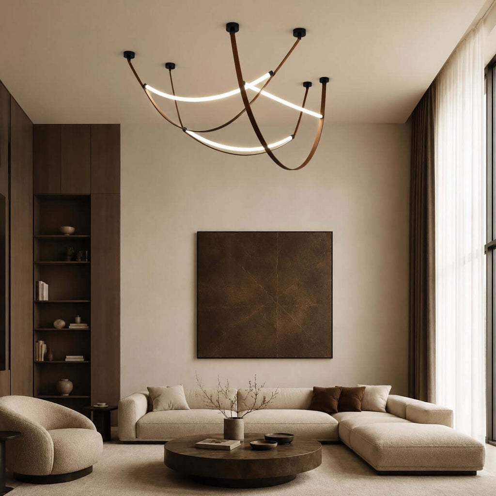 Three lit Clérachic loop pendants sweep across a high ceiling above a sectional sofa, a round coffee table and a dark framed artwork.