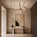 In a hallway, a Clérachic three-loop pendant in gold and brown hangs above a stone console and a large abstract painting.