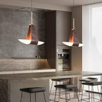 Two Clérachic Leather Pendant Lights over a marble kitchen island, brown straps cradling white boat diffusers.