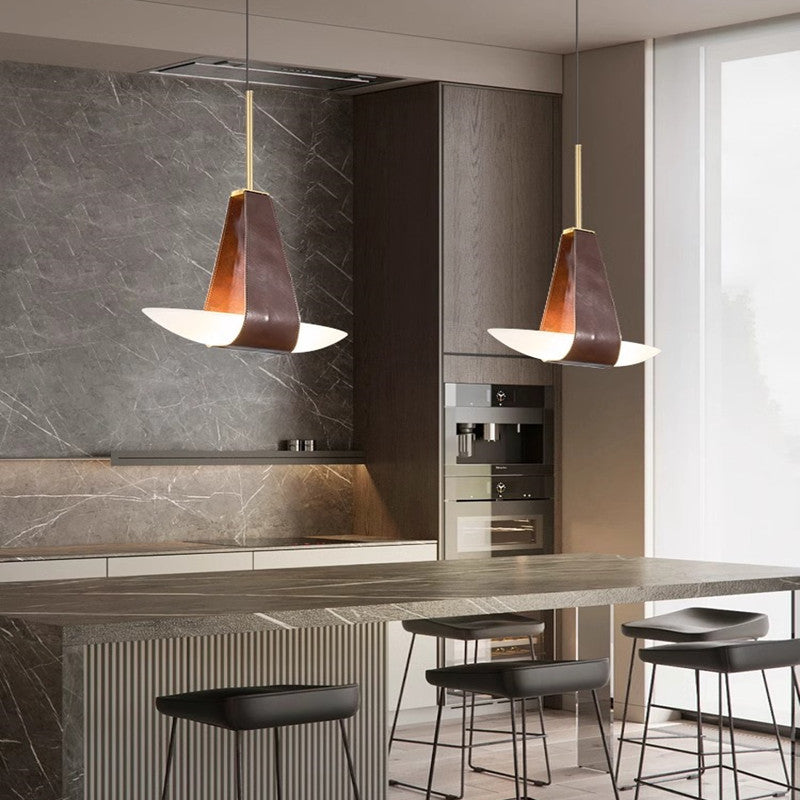 Two Clérachic Leather Pendant Lights over a marble kitchen island, brown straps cradling white boat diffusers.