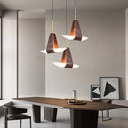 A three-drop Clérachic Leather Pendant Light cluster hangs at mixed heights over a dark wood dining table.