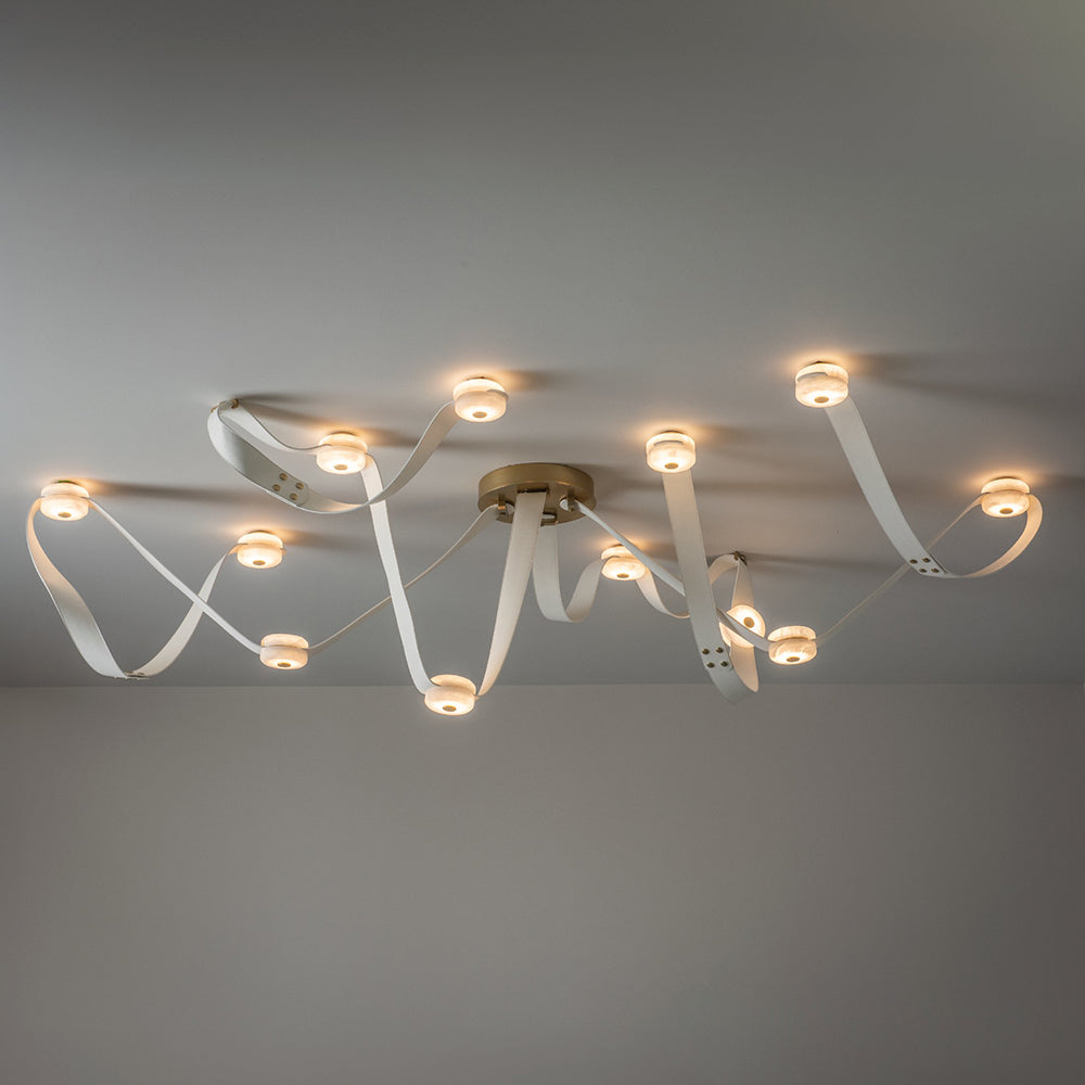 The 12-head Clérachic Leather Strap Chandelier in white leather with a brass canopy, spread wide across a ceiling.