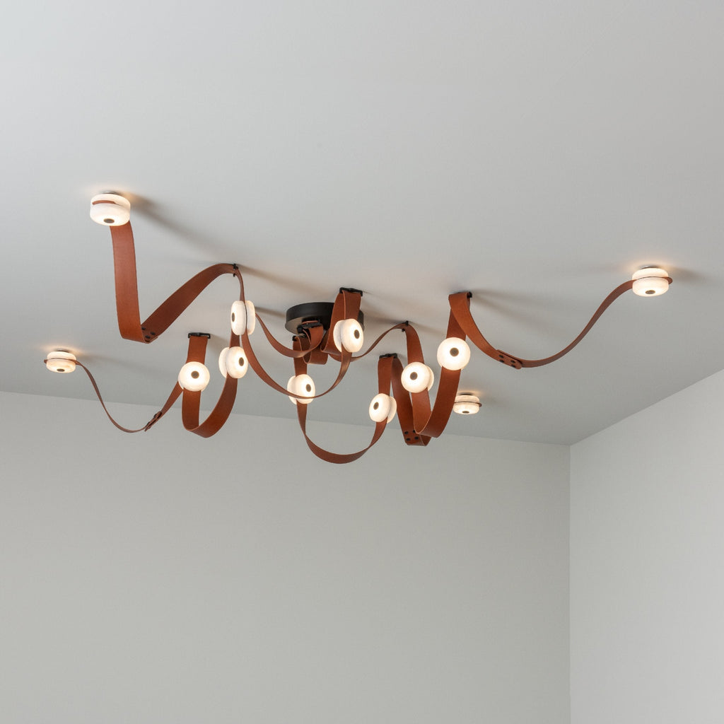 Cognac leather and black fittings on the Clérachic Leather Strap Chandelier, twelve alabaster discs lit across the ceiling.