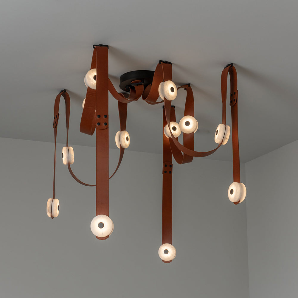 The Clérachic Leather Strap Chandelier with cognac straps dropping in long vertical lines from a black ceiling canopy.