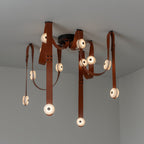 The Clérachic Leather Strap Chandelier with cognac straps dropping in long vertical lines from a black ceiling canopy.