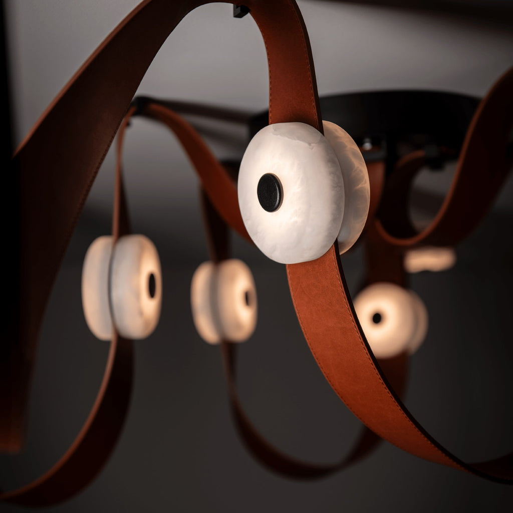 Macro of one alabaster disc on the Clérachic Leather Strap Chandelier, veining lit from within on a tan leather strap.