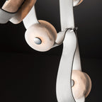 White leather straps and alabaster discs on the Clérachic Leather Strap Chandelier, shot against a black background.