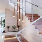Cognac Clérachic Leather Strap Chandelier falling down a travertine stairwell beside a glass and steel balustrade.
