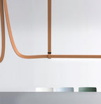 Close view of a tan leather strap fixed to a horizontal light bar with a black clasp, from Clérachic.
