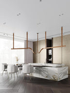 Tan strap pendants carrying light bars above a marble kitchen island and round upholstered chairs, from Clérachic.