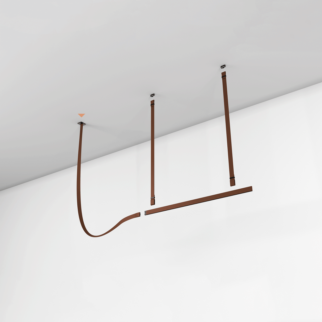Rust-brown strap pendant mounted on a white ceiling and wall, its light bar hung from leather straps, from Clérachic.