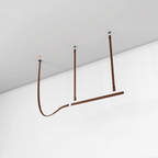 Rust-brown strap pendant mounted on a white ceiling and wall, its light bar hung from leather straps, from Clérachic.