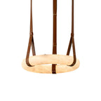 Clérachic's leather-strap ring chandelier seen close up, brown belts riveted in brass cradling the glowing alabaster ring.