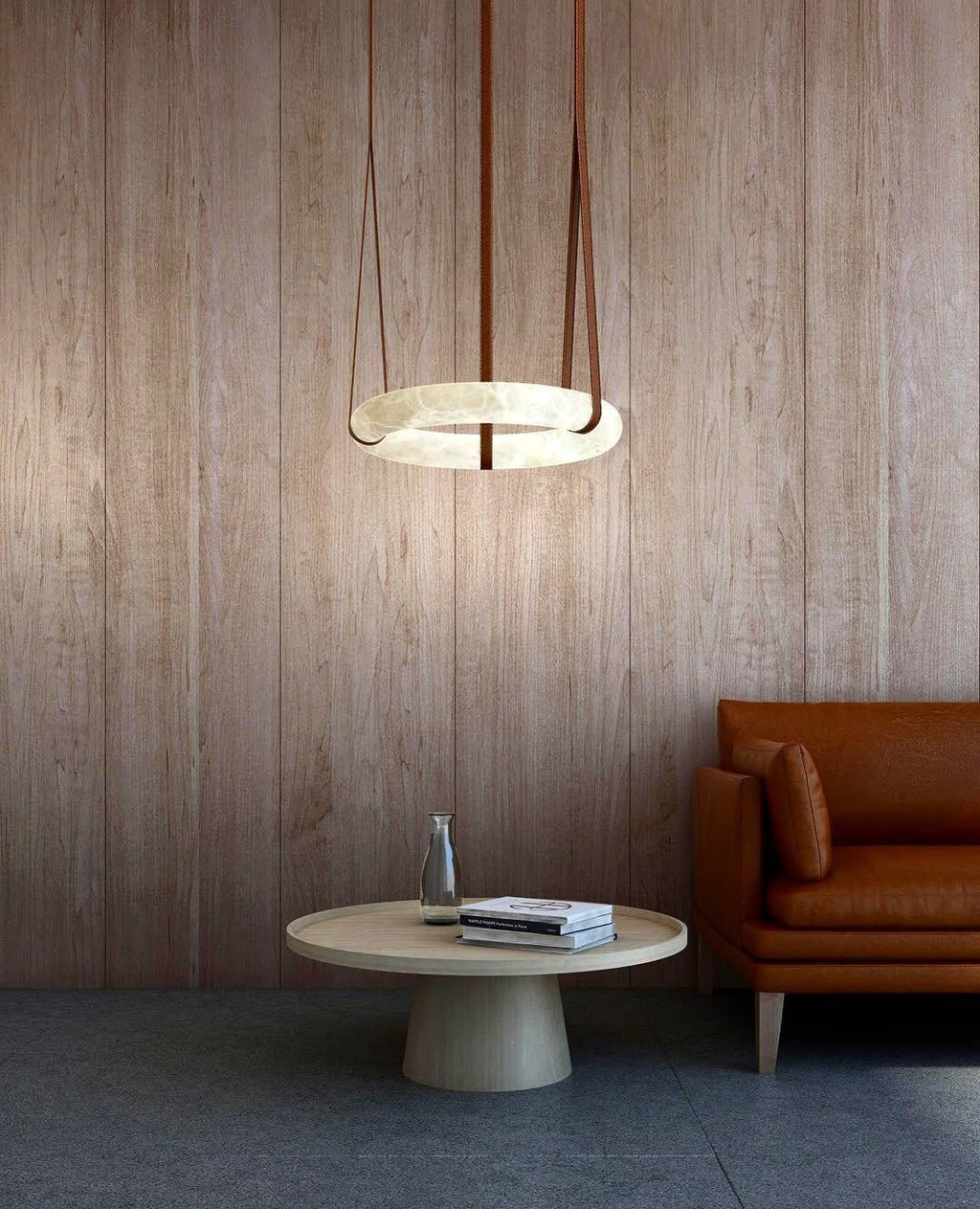A Clérachic alabaster ring chandelier lit above a round wood coffee table against a slatted timber wall in a calm sitting room.