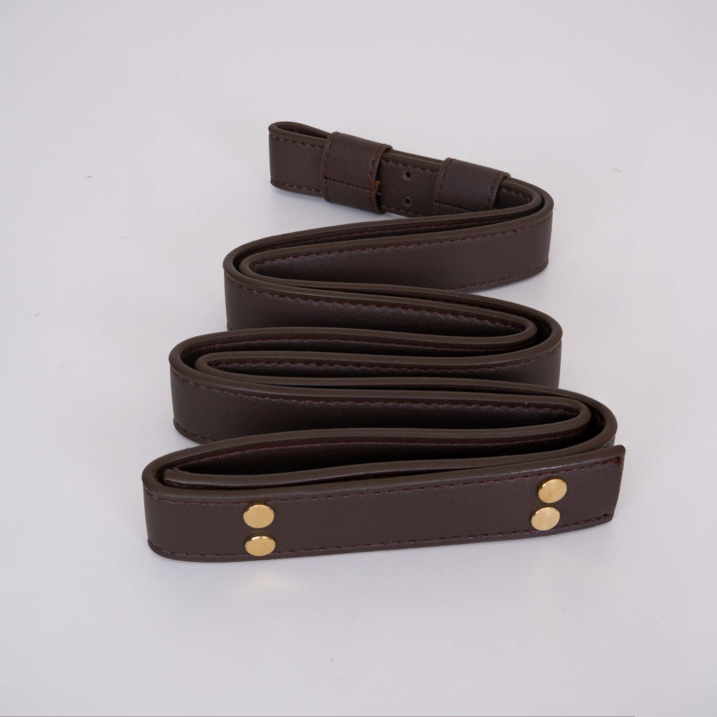 Dark chocolate leather suspension belt for the Clérachic ring chandelier, coiled to show its edge stitching and brass rivets.