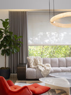 A Clérachic alabaster ring chandelier glowing at the frame edge above a boucle sofa, red lounge chair and fiddle-leaf fig.