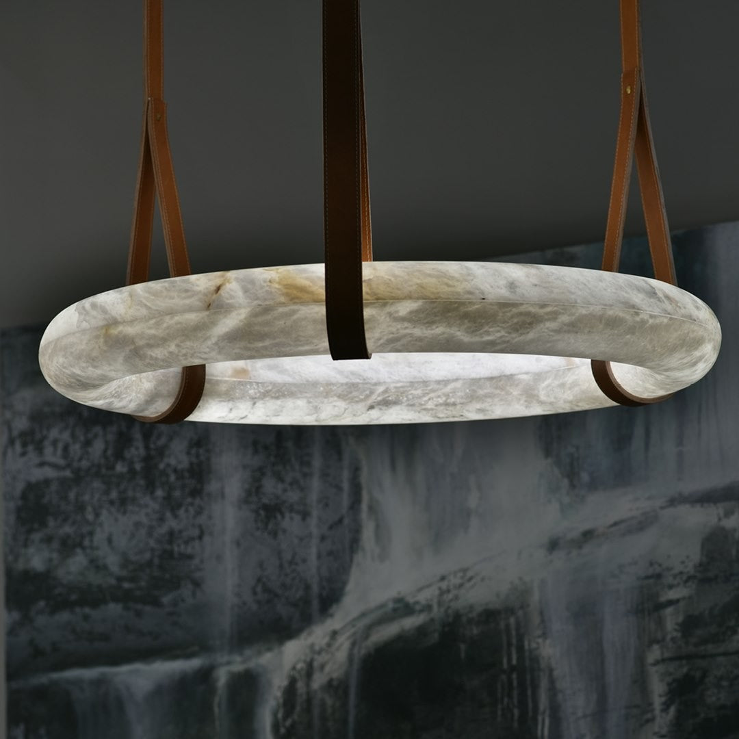Close view of the unlit Clérachic ring, cool off-white alabaster clouded with grey and honey, held in three leather belts.