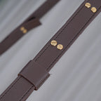Detail of the Clérachic chandelier's leather belt, closed with paired slotted brass screws above a stitched keeper loop.