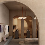 A Clérachic alabaster ring chandelier lighting an arched plaster alcove in a boutique, hung on tan leather belts.