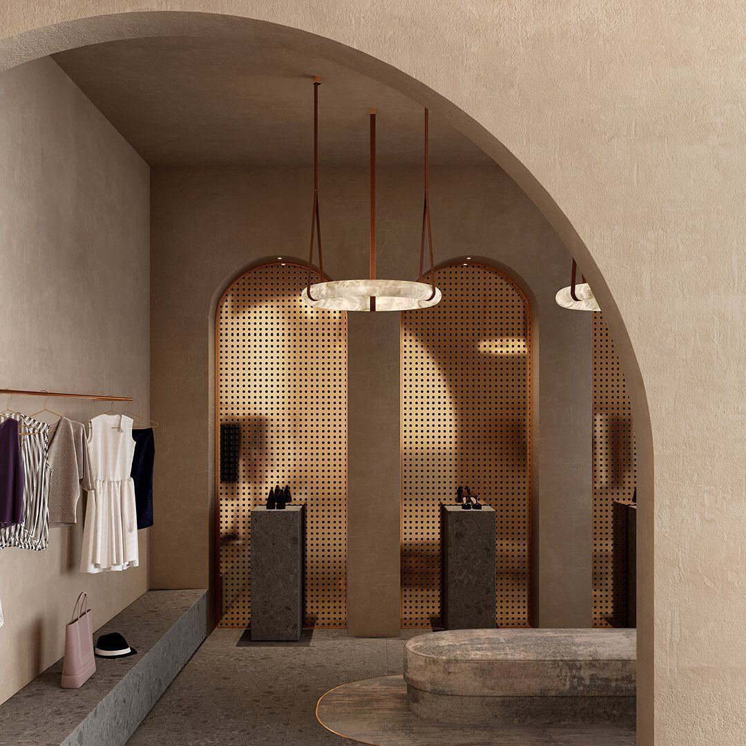 A Clérachic alabaster ring chandelier lighting an arched plaster alcove in a boutique, hung on tan leather belts.