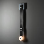 The long one-head Clérachic Leather Strap Wall Sconce in black leather, a single alabaster disc lit at the strap's end.