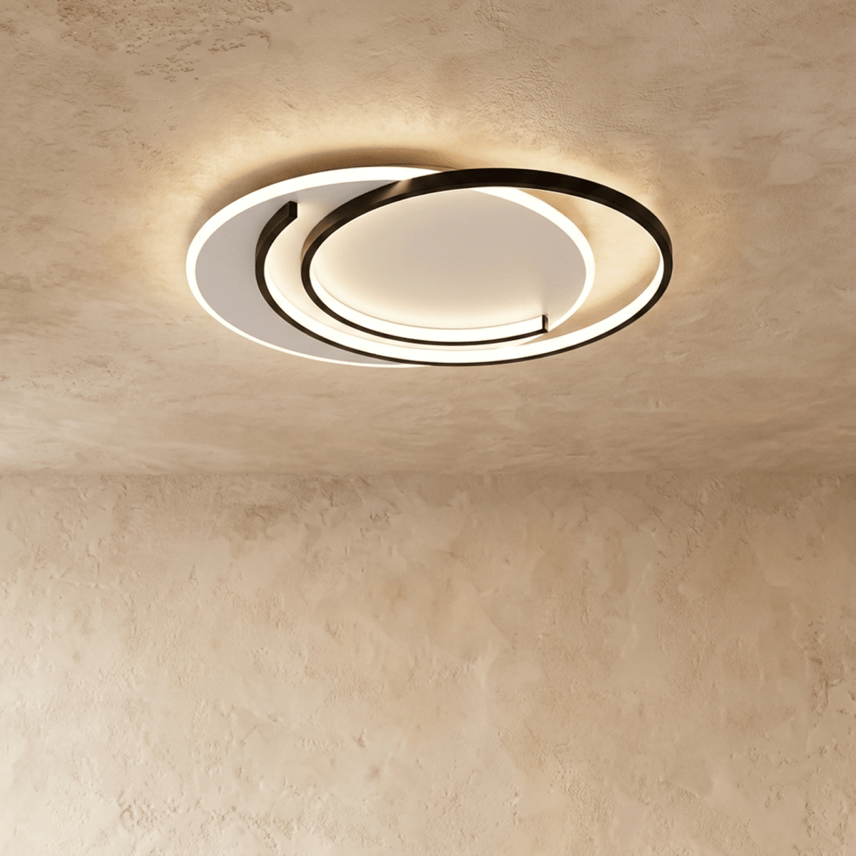 Clérachic flush ceiling light of black aluminium rings in a crescent layout, glowing warm on a limewash ceiling.