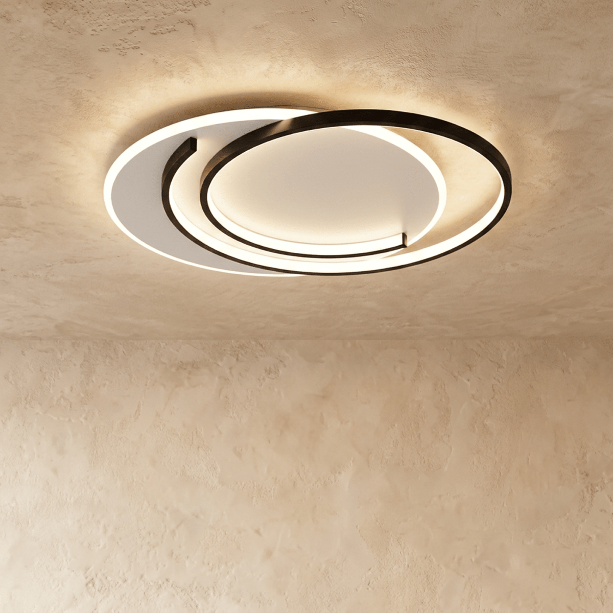 Clérachic wider flush ceiling light with black crescent-layout rings and a lit white diffuser on a limewash ceiling.