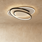 Clérachic wider oval flush ceiling light with a swirling black frame and a glowing white diffuser on limewash.