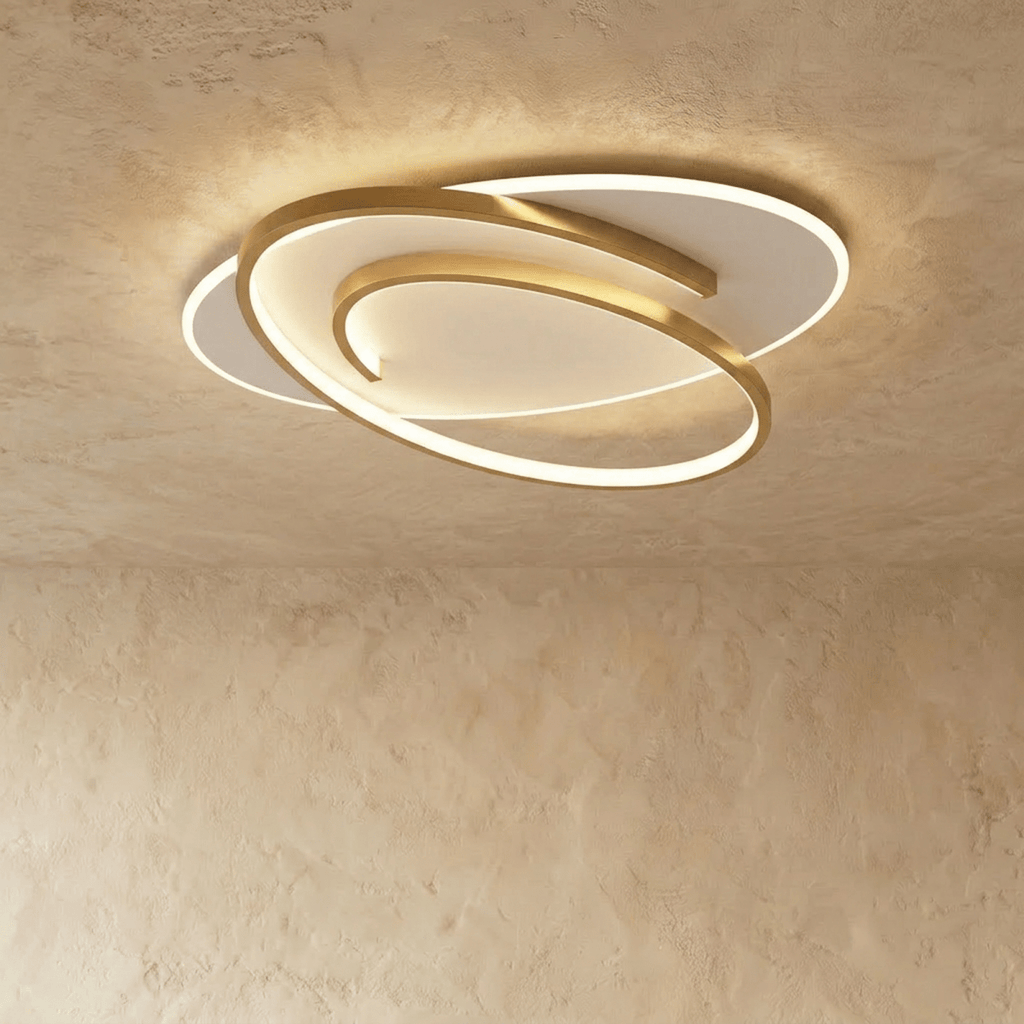 Clérachic wider oval flush ceiling light with a swirling gold frame and a glowing white diffuser on limewash.
