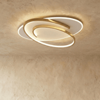 Clérachic wider oval flush ceiling light with a swirling gold frame and a glowing white diffuser on limewash.