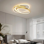 Clérachic oval ceiling light with a swirling gold frame above a grey bed, tall window and white curtain.