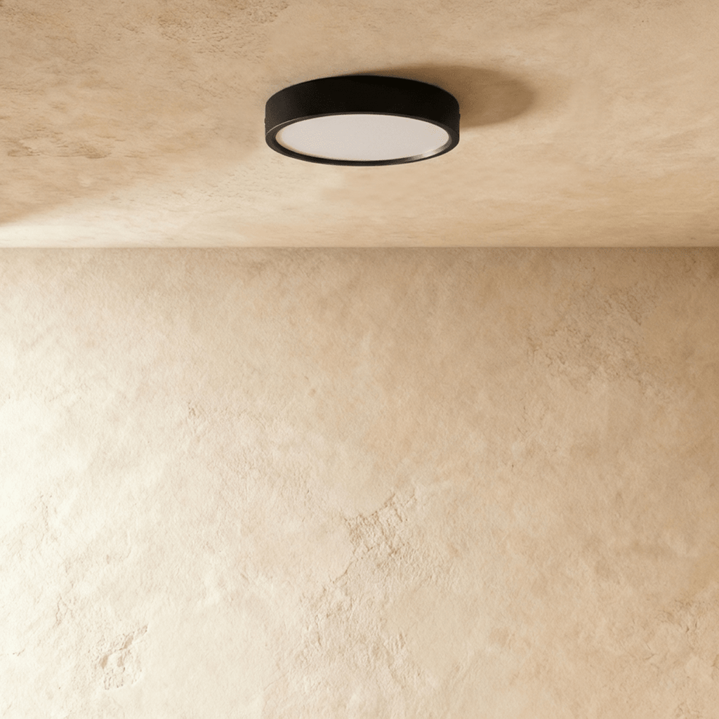 Clérachic slim round black surface-mounted LED downlight switched off, its frosted white diffuser visible on a limewash ceiling.