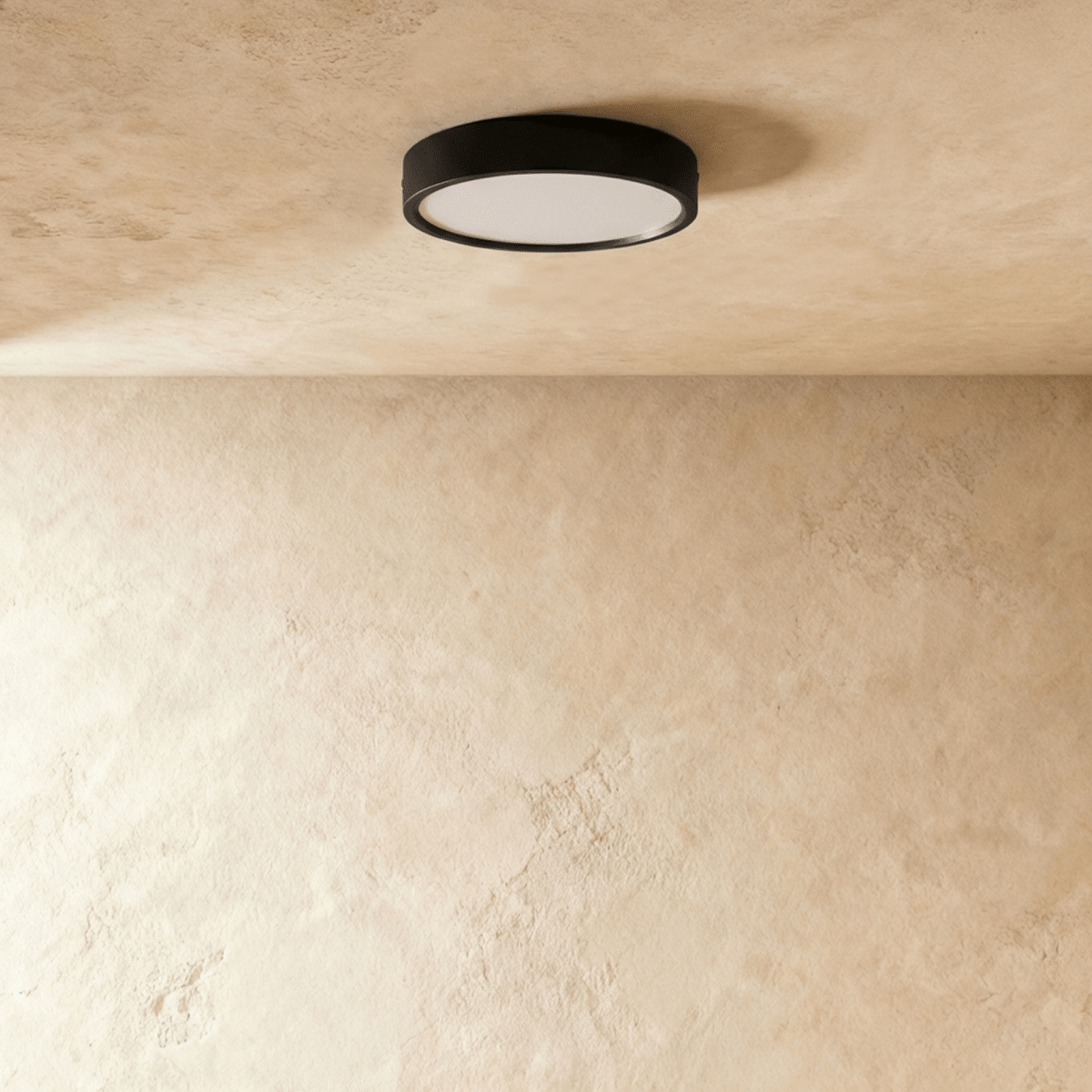 Clérachic slim round black surface-mounted LED downlight switched off, its frosted white diffuser visible on a limewash ceiling.