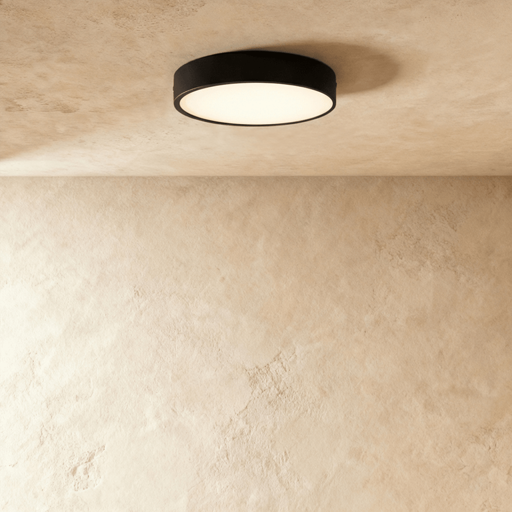 Clérachic larger round black surface-mounted LED downlight with a wide frosted diffuser, lit on a textured plaster ceiling.