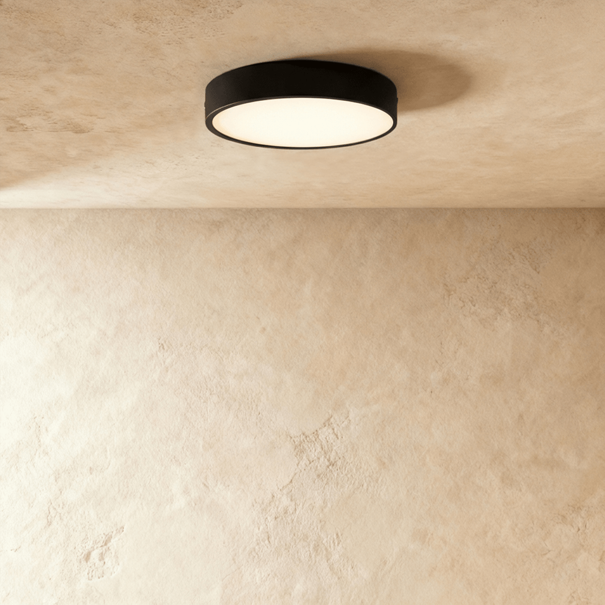 Clérachic larger round black surface-mounted LED downlight with a wide frosted diffuser, lit on a textured plaster ceiling.