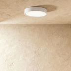 Clérachic larger round white surface-mounted LED downlight with a broad frosted diffuser, lit on a plaster ceiling.