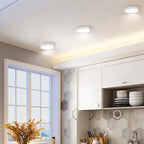 Clérachic three white round surface-mounted downlights above a bright kitchen with hexagonal tiles and a window.