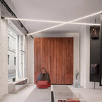 Two Clérachic strip lights cross the ceiling of a bright boutique, above a rust-red wooden wall and a pair of handbags.