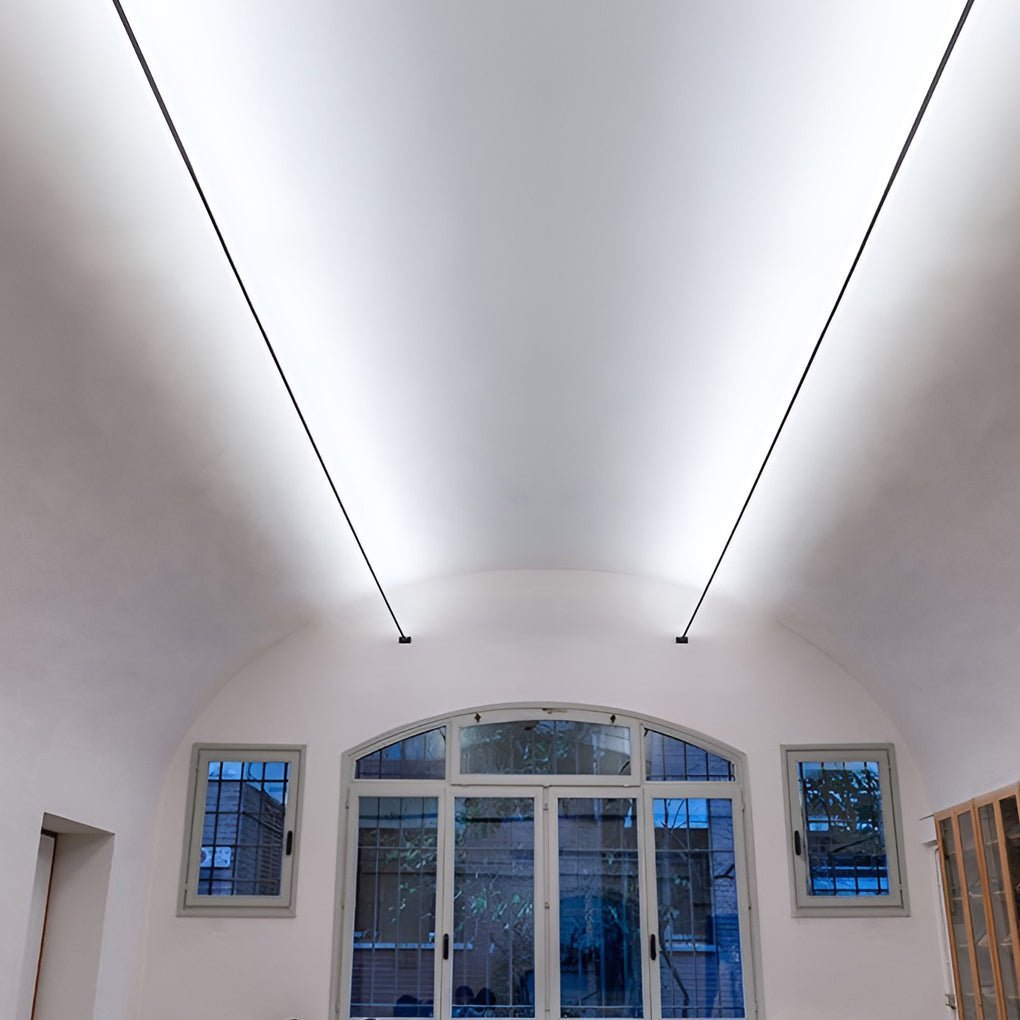 Two long Clérachic strip lights slope up a vaulted ceiling, washing it with bright white light above tall arched windows.