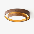 This Clérachic flush ceiling light on a white backdrop, with two stacked walnut wood-grain rings and a warm glow inside the lower ring.