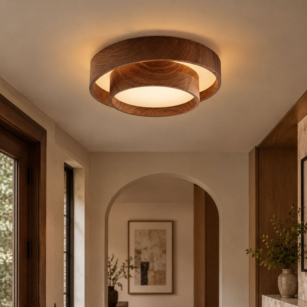 Clérachic ceiling light with two wood-grain rings, glowing in a hallway with an arched alcove, a framed print and a leafy vase.
