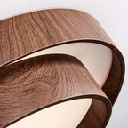 Close view of the fine walnut grain pattern and curved edge of the stacked rings on this Clérachic ceiling light.