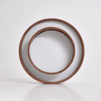 Clérachic ceiling light standing on edge on a pale surface, so both wood-grain rings and the white diffuser face the camera.