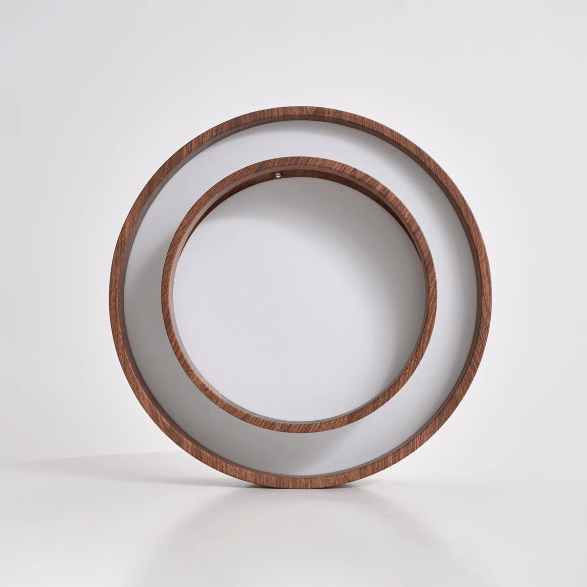 Clérachic ceiling light standing on edge on a pale surface, so both wood-grain rings and the white diffuser face the camera.
