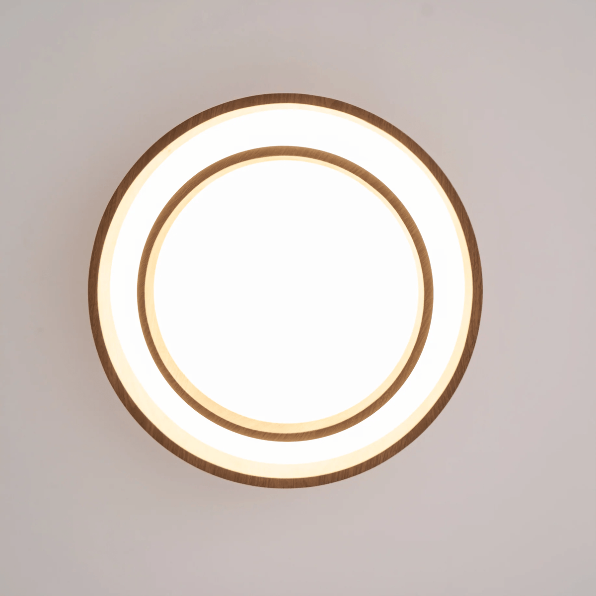 Clérachic ceiling light seen from directly below, lit, with an outer ring, a glowing white band and a smaller inner ring.